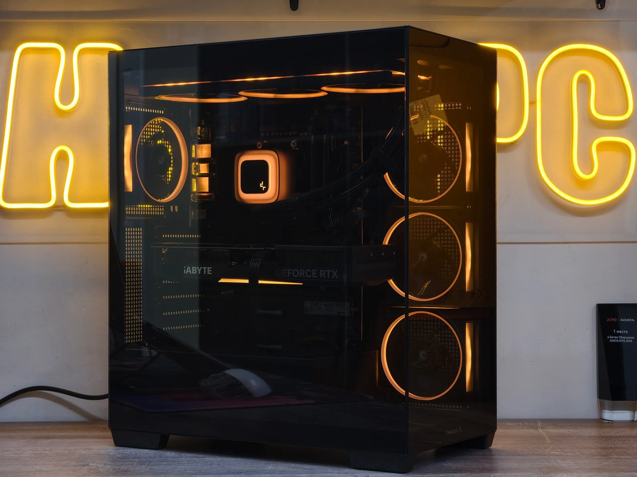 Игровая сборка HappyPC с янтарной подсветкой на фоне фирменной неоновой вывески