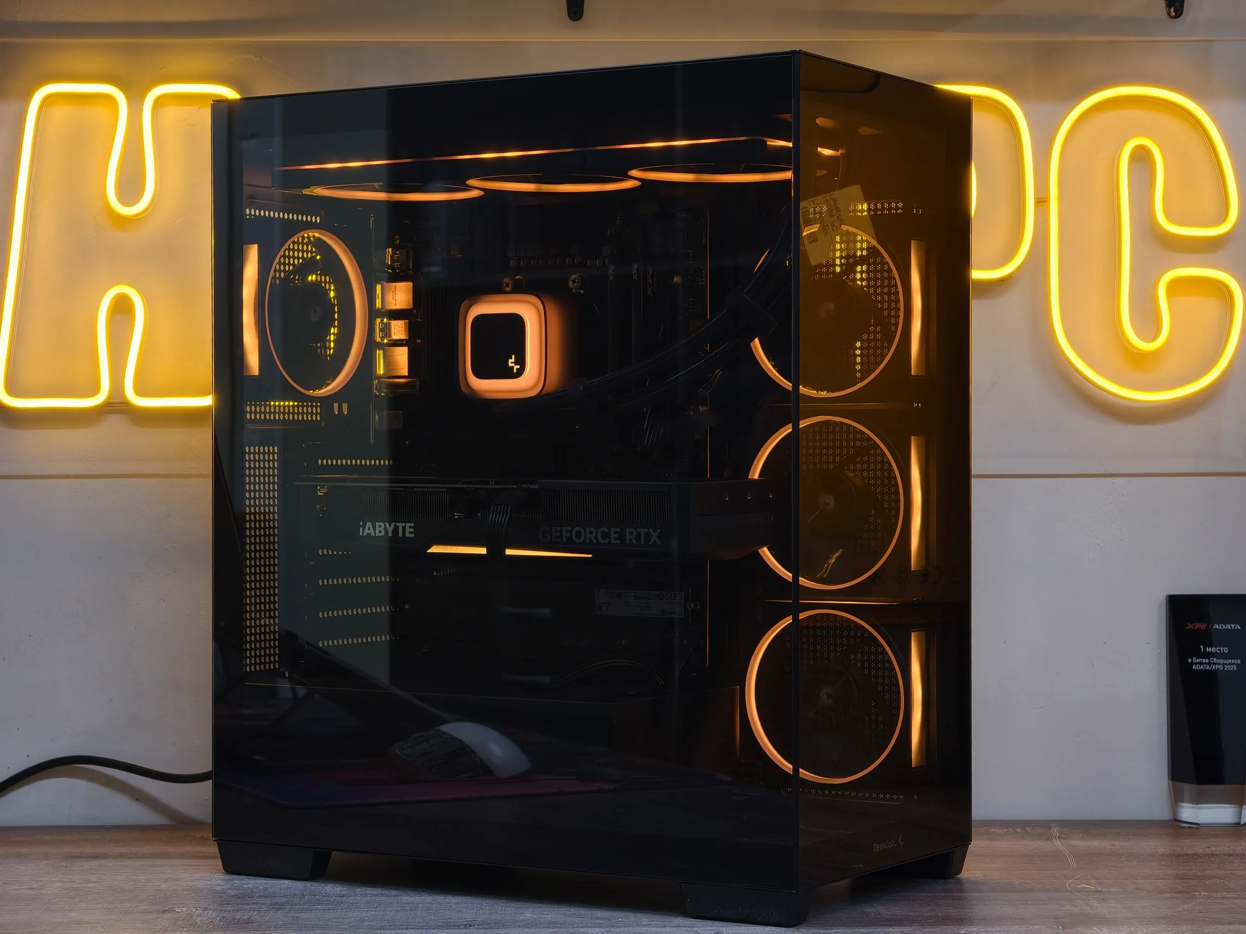 Игровая сборка HappyPC с янтарной подсветкой на фоне фирменной неоновой вывески